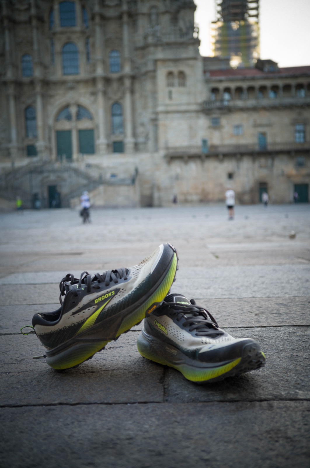 A different angle of the same worn Cascadia 20s propped against the cathedral square stones in Santiago de Compostela.